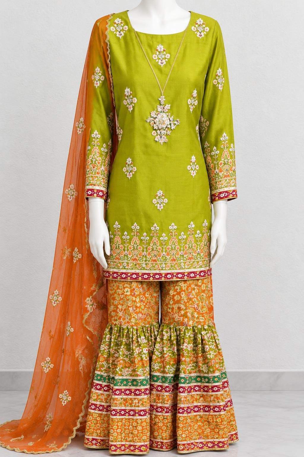Dhani green embroidered shirt with printed garara and orange dupatta on a mannequin